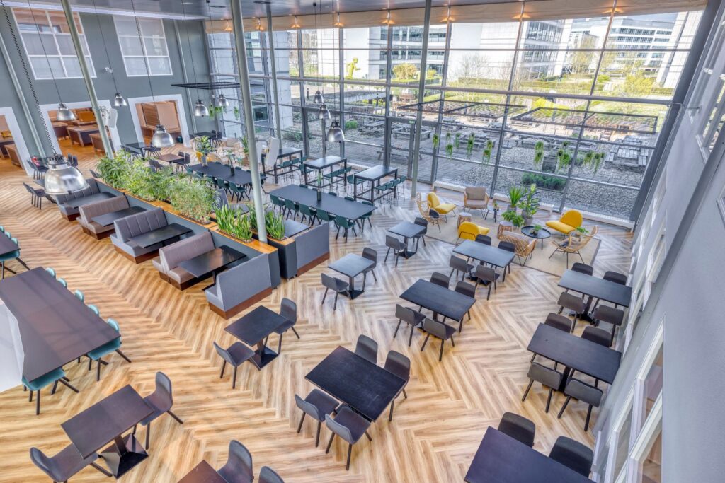 Moderne en ruim opgezette kantine aan de Spicalaan met grote ramen, diverse zitplekken en uitzicht op een dakterras.