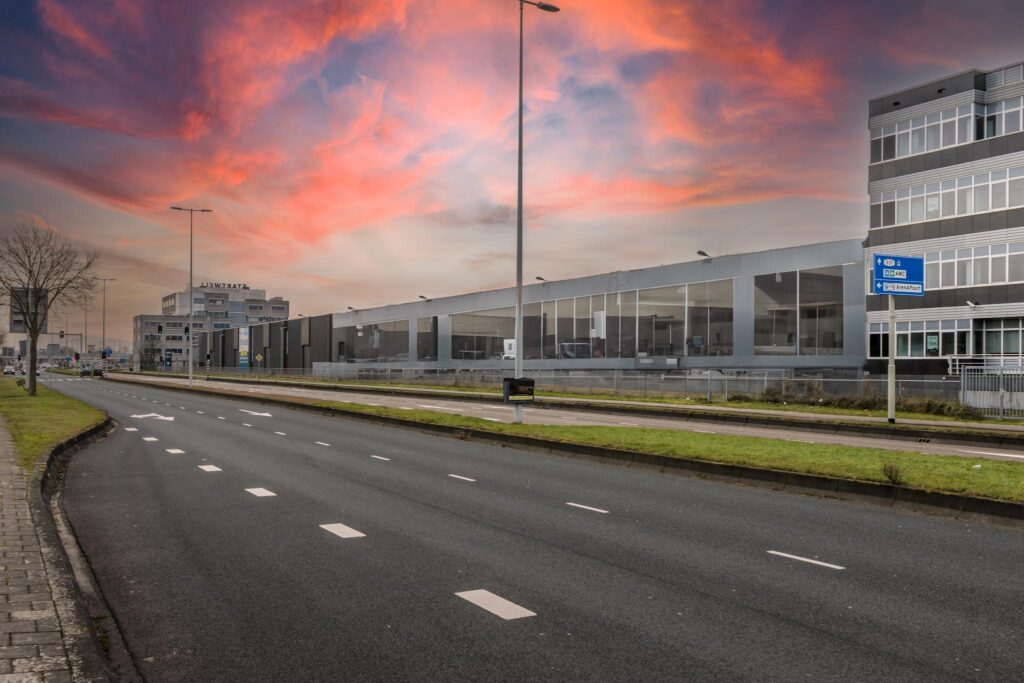 Lege Lemelerbergweg in een industriegebied bij zonsondergang met zicht op het gebouw van "Startwell".