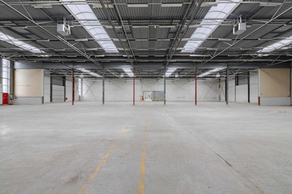 Lege bedrijfshal met betonnen vloer en metalen dak, gelegen aan de Lemelerbergweg.