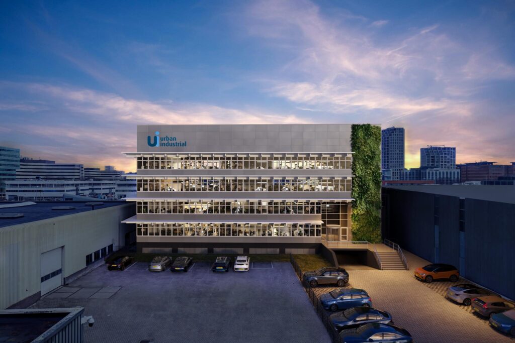 Kantoorgebouw aan de Lemelerbergweg met Urban Industrial-logo, voorzien van een groene gevel en omringd door geparkeerde auto's bij zonsondergang.