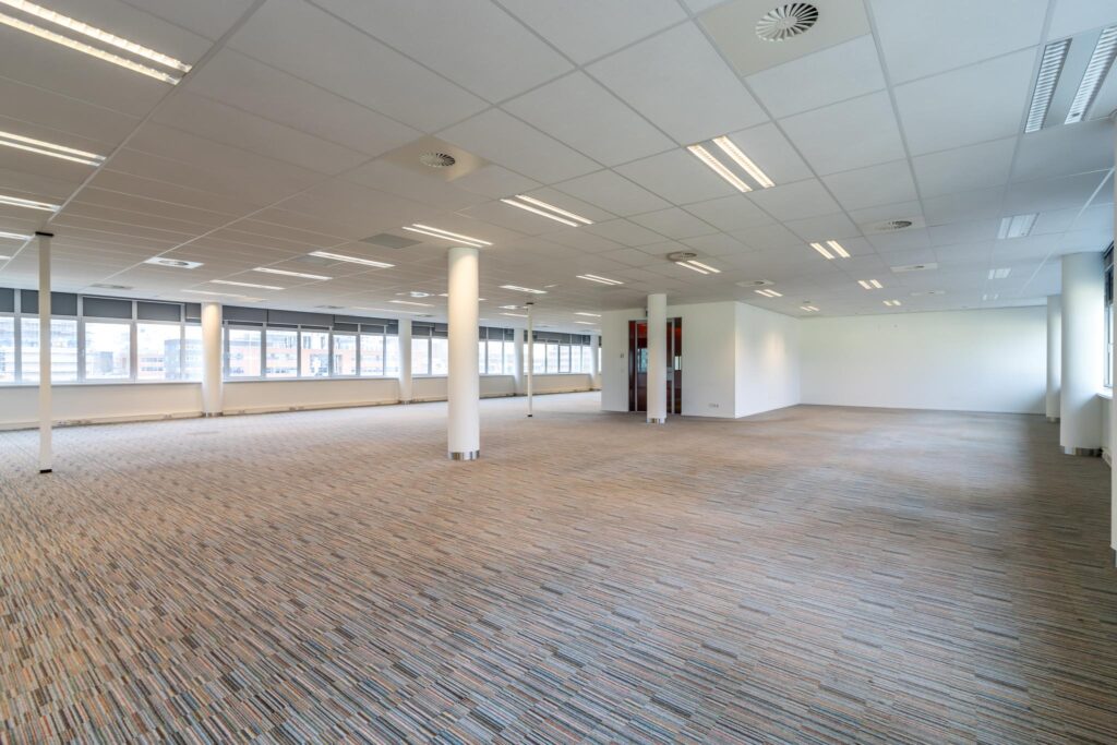 Leeg en ruim kantoorinterieur aan de Lemelerbergweg met grote ramen en systeemplafond.