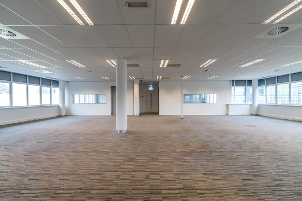 Leegstaand kantoorruimte op de Lemelerbergweg met tapijtvloer, systeemplafond en grote ramen.