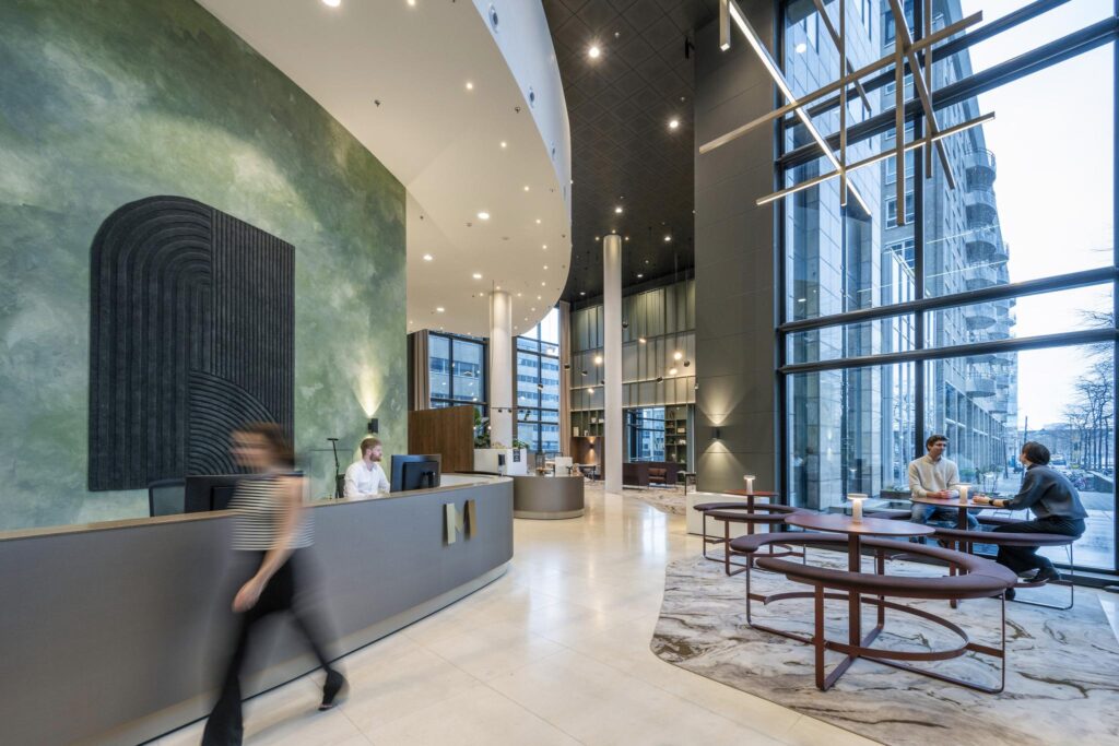 Moderne en ruime entreehal van Amstelplein met receptiebalie, zitgedeelte en grote raampartijen.