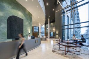 Moderne en ruime entreehal van Amstelplein met receptiebalie, zitgedeelte en grote raampartijen.