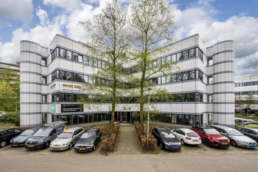 Vooraanzicht van een modern kantoorgebouw met de naam 'Entrada', omgeven door geparkeerde auto's en bomen.