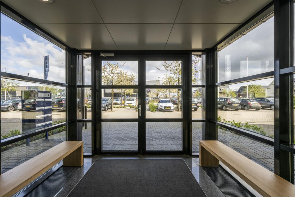 View from inside a glass entrance area on Singaporestraat, showing parked cars and trees outside.