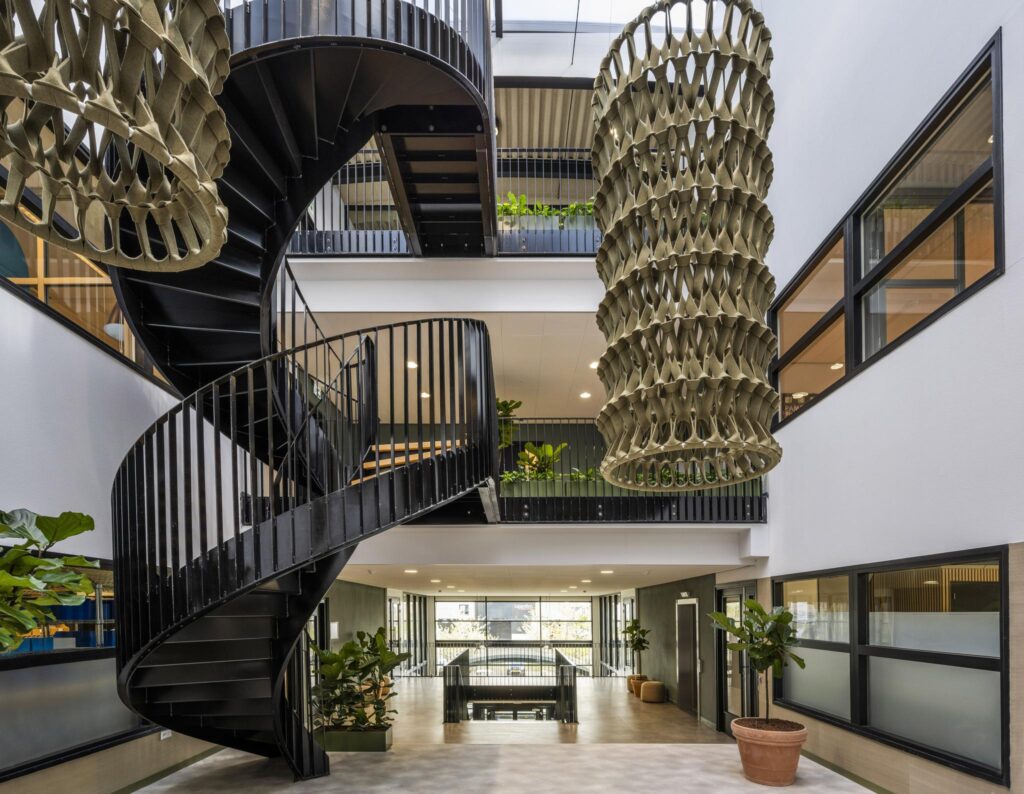 Modern interior of a building on Singapore Street featuring a black spiral staircase, large hanging sculpture, and indoor plants.