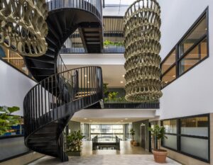 Modern interior of a building on Singapore Street featuring a black spiral staircase, large hanging sculpture, and indoor plants.