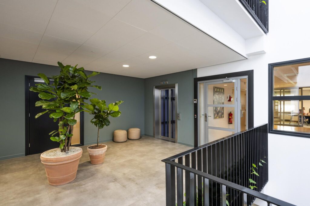 Modern hallway in a building on Singaporestraat with potted plants, an elevator, and access to offices.