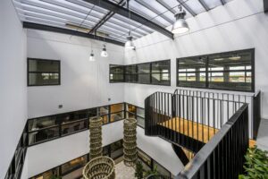Modern atrium in an office building on Singaporestraat with black-framed windows, hanging light fixtures, and an open staircase.