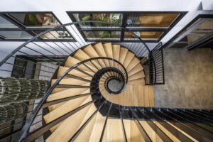 Top view of a modern spiral staircase with wooden steps and black railings in an office building on Singaporestraat.
