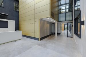 Moderne, overdekte entreehal van een kantoorpand aan de Laarderhoogtweg met strakke lijnen en glazen elementen.