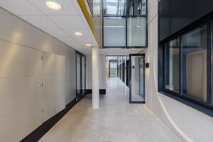 Moderne, lichte gang in een kantoorpand aan de Laarderhoogtweg met glazen deuren en betonnen vloer.
