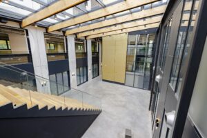 Licht en modern atrium met glazen dak en houten trap in een kantoorgebouw aan de Laarderhoogtweg.