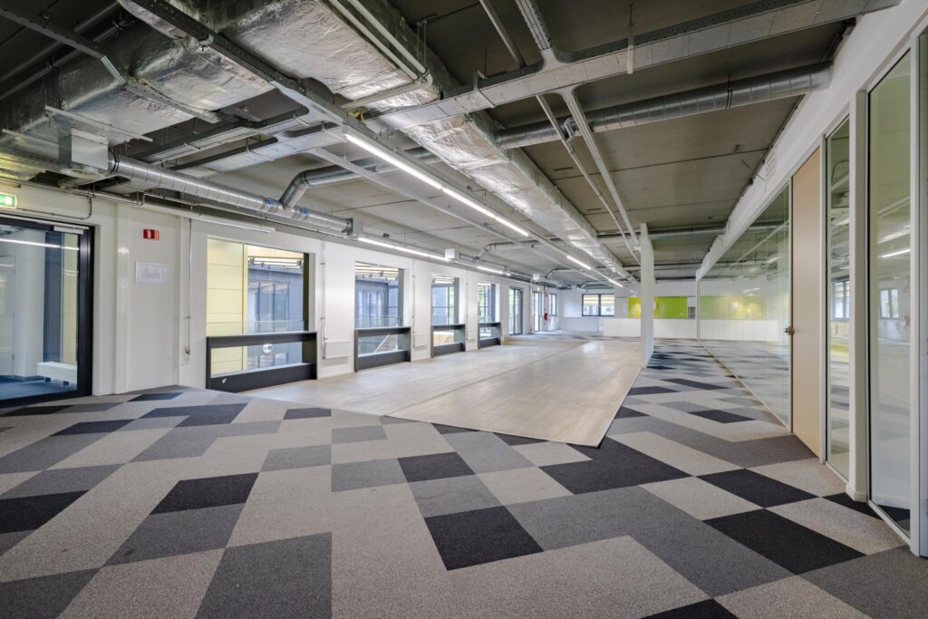 Moderne, industriële kantoorruimte aan de Laarderhoogtweg met geometrisch tapijtpatroon en grote ramen.