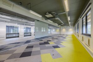 Leeg kantoorpand aan de Laarderhoogtweg met glazen wanden en geometrisch patroon in het tapijt.