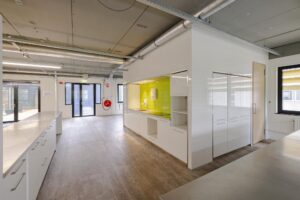Moderne, open kitchenette met felgroene tegelwand in een licht industrieel kantoorpand aan de Laarderhoogtweg.