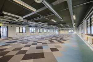 Leeg kantoorruimte aan de Laarderhoogtweg met industriële plafondafwerking en vloerbedekking in patroon van grijze en blauwe vlakken.