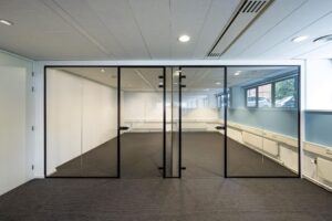 Moderne, lege kantoorruimte met glazen wand en zwarte deurkozijnen in het gebouw aan de Stroombaan.