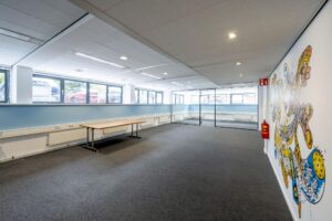 Moderne kantoorruimte met een muurschildering, grote ramen en glazen scheidingswand in een gebouw aan de Stroombaan.