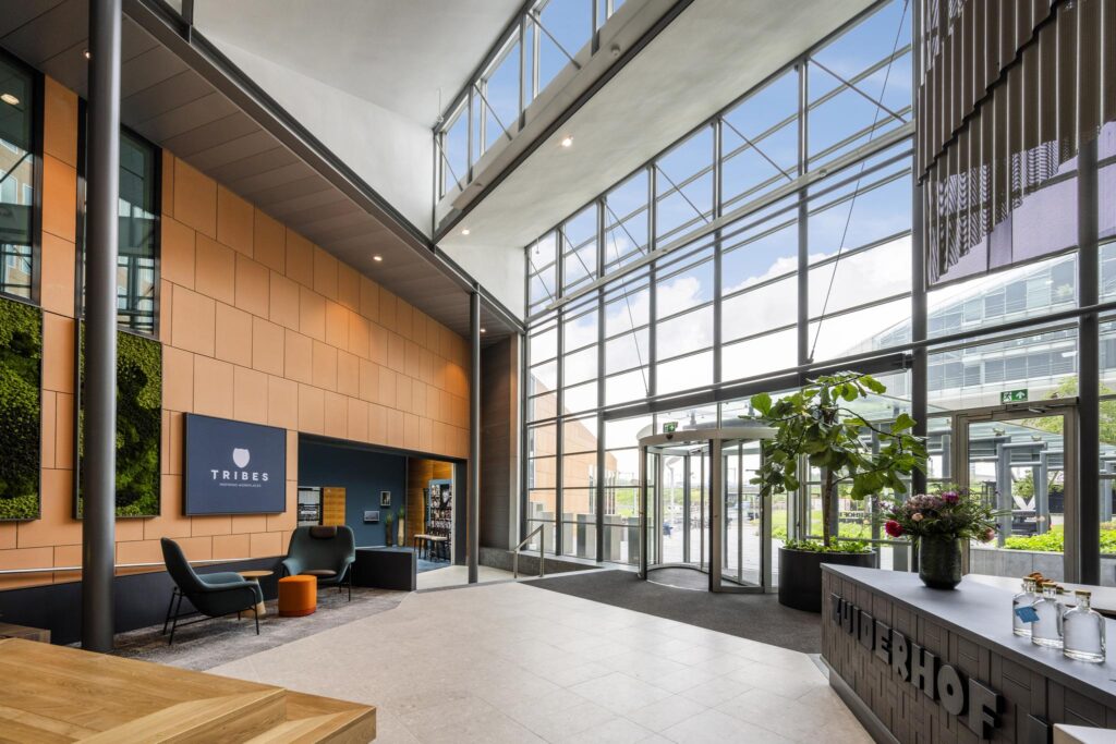 Modern entrance hall of Tribes coworking space on Jachthavenweg with large glass windows, seating area, and reception desk.
