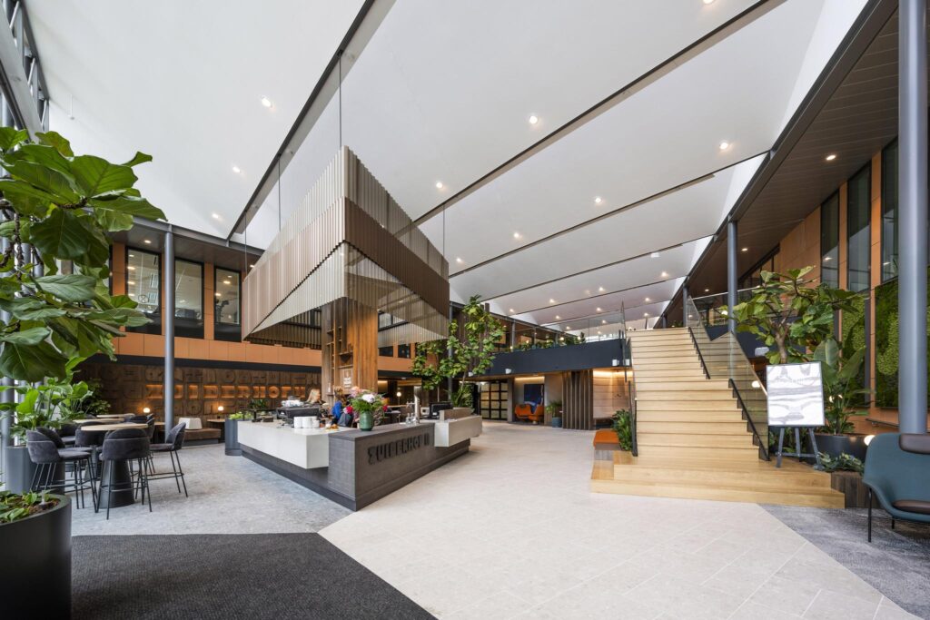 Modern lobby interior of the Zuiderhof building on Jachthavenweg, featuring a coffee bar, wooden staircase, and indoor greenery.