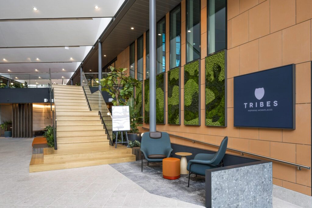 Modern lobby of Tribes Inspiring Workplaces at Jachthavenweg with wooden staircase, lounge seating, and green wall panels.