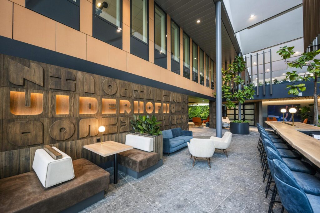 Modern lounge area in a spacious office building on Jachthavenweg with stylish seating, greenery, and decorative wooden wall panels.