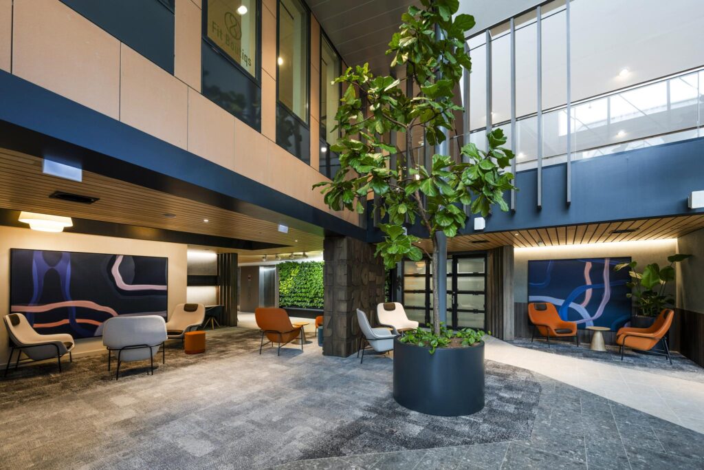 Modern office lobby at Jachthavenweg with contemporary seating, a large indoor plant, and abstract wall art.