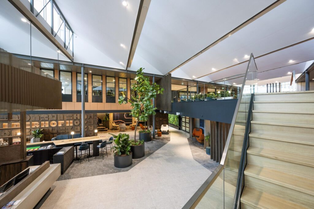 Modern and spacious office interior on Jachthavenweg with open seating areas, indoor plants, and a wooden staircase.