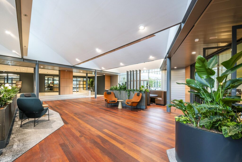 Modern lobby area at Jachthavenweg featuring wooden floors, indoor plants, and stylish seating.