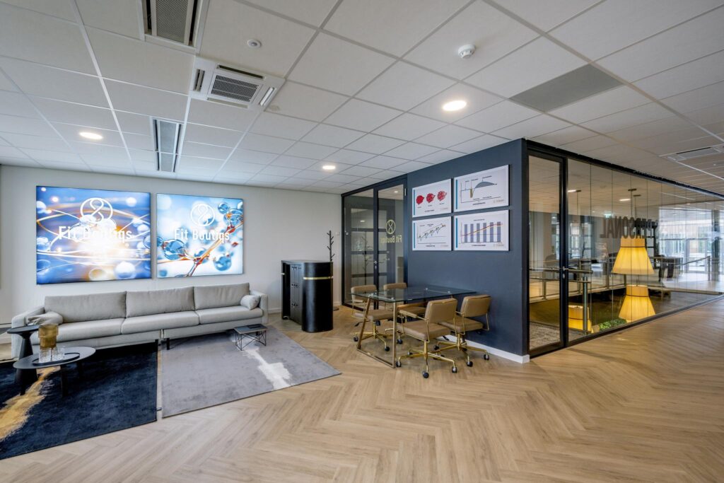 Modern office interior of Fit Boutiqs with a lounge area, glass meeting room, and scientific-themed wall art.