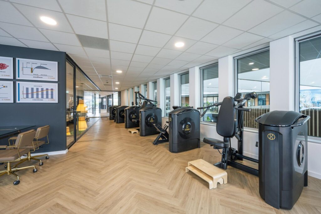 Modern fitness area at Jachthavenweg with a row of high-tech exercise machines and large windows.
