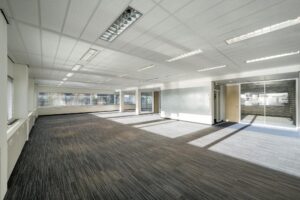 Ruim, licht en modern kantoorinterieur aan de Spaklerweg met vloerbedekking en grote ramen.