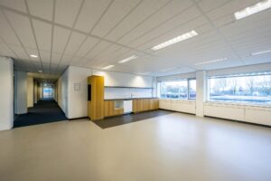Lichte kantoorkeuken aan de Spaklerweg met inbouwkasten, grote ramen en uitzicht op de stad.