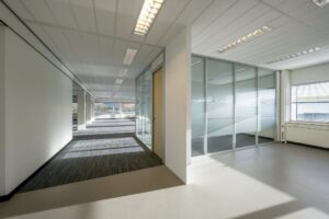Licht en modern kantoorpand aan de Spaklerweg met glazen scheidingswanden en grote ramen.