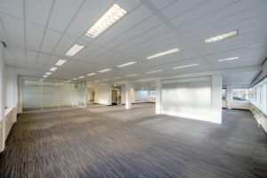 Ruime, moderne en leegstaande kantoorruimte aan de Spaklerweg met tapijtvloer, systeemplafond en glazen scheidingswand.