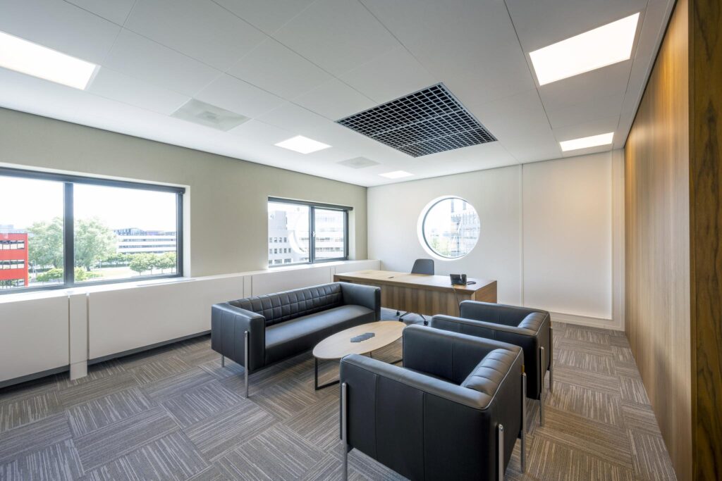 Modern office space on Wegalaan with a wooden desk, black leather seating, and large windows providing natural light.