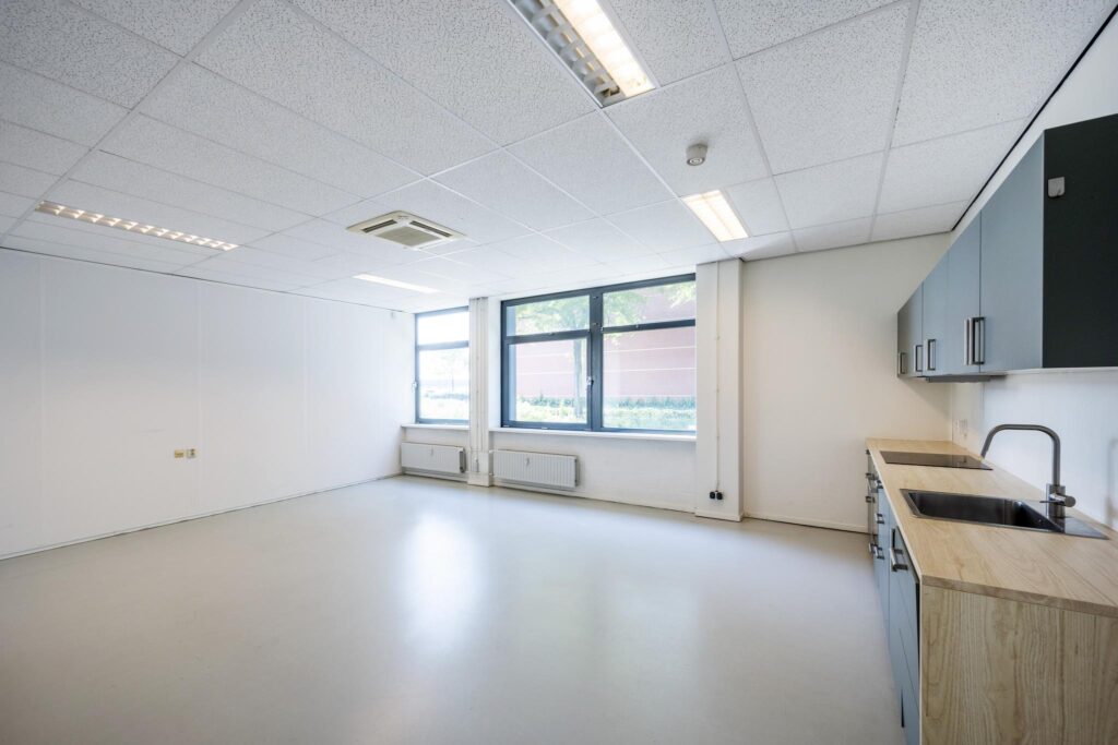 Lichte, lege kantoorruimte aan de Breguetlaan met grote ramen en een keukenblok.