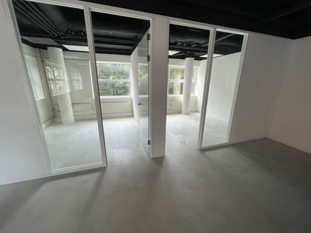 Modern, empty office space with glass-walled rooms and large windows.