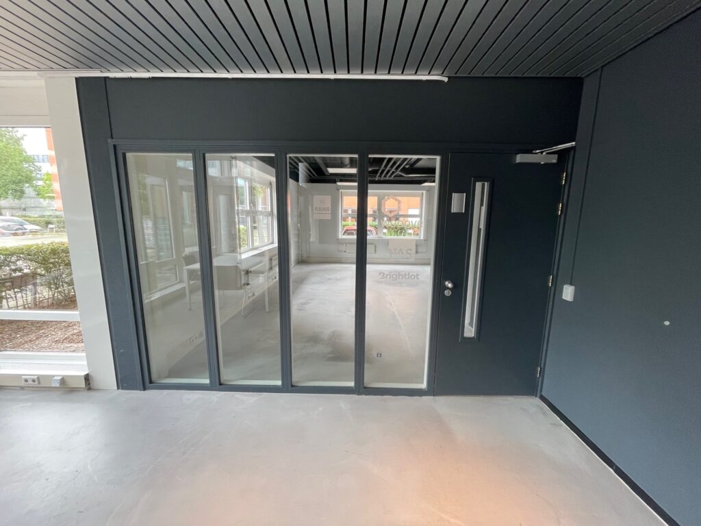 Glass entrance with dark frames leading into a modern office space labeled "Brightlot."