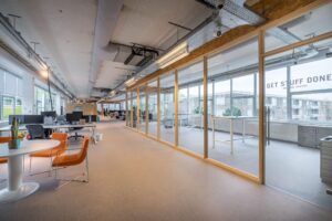 Modern open kantoorinterieur aan de Helmholtzstraat met flexwerkplekken en vergaderruimte met glazen wanden.