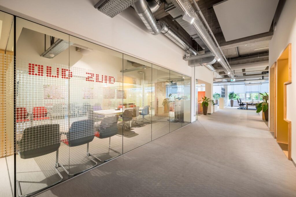 Moderne kantoorruimte met glazen vergaderruimte genaamd "Oud Zuid" en open werkplekken in de Helmholtzstraat.