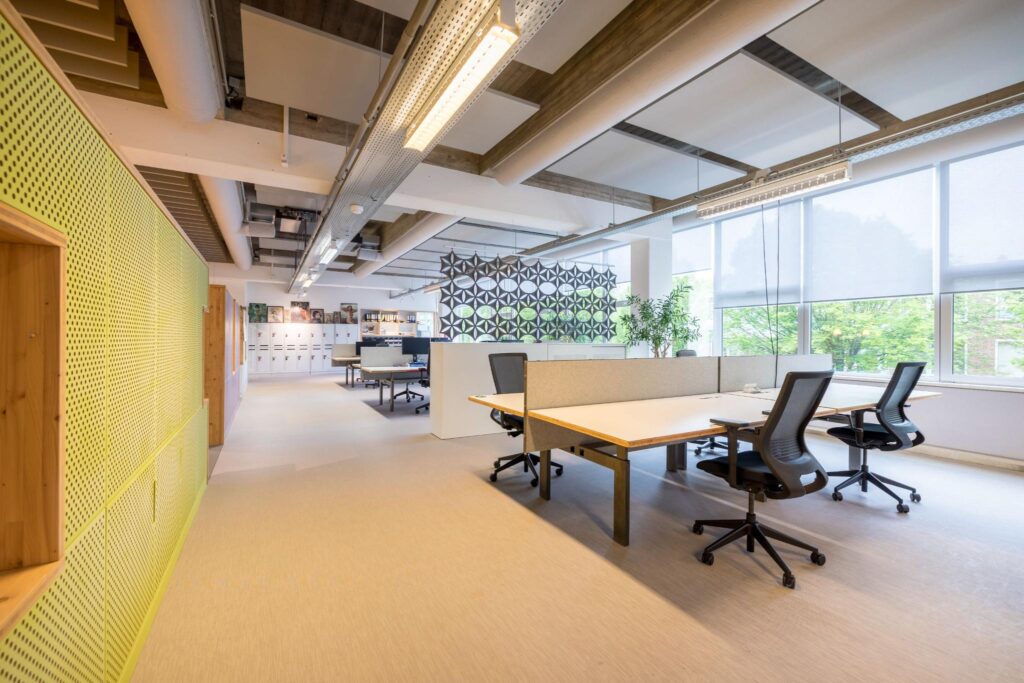 Modern en licht kantoorinterieur aan de Helmholtzstraat met werkplekken, designscheidingswand en grote ramen.