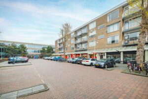 Winkelpand met bovenliggende appartementen aan de Helmholtzstraat met geparkeerde auto's en fietsen op de voorgrond.