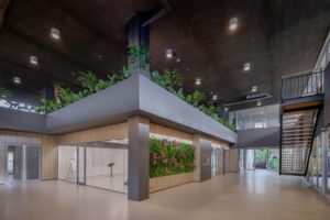 Moderne ontvangsthal aan de Helmholtzstraat met veel groen, glazen wanden en een stalen trap.