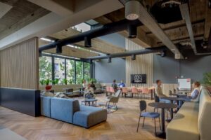 Moderne, open kantoorlounge aan de Helmholtzstraat met zithoeken, vergadertafels en het Merin-logo aan de muur.
