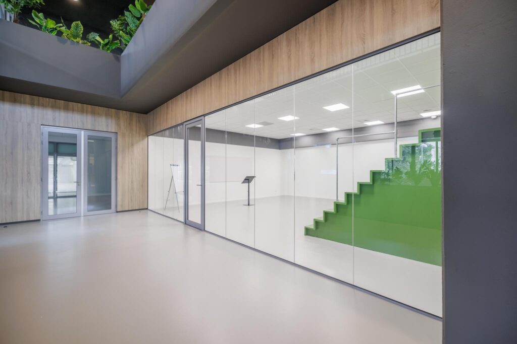 Moderne kantoorruimte aan de Helmholtzstraat met glazen wanden en een groene traptribune in het interieur.