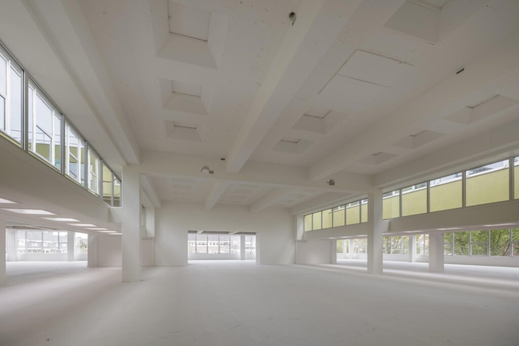 Lichte, open ruimte in een leegstaand gebouw aan de Helmholtzstraat met grote ramen en hoge plafonds.