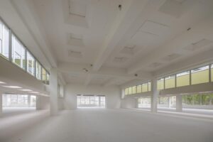 Lichte, open ruimte in een leegstaand gebouw aan de Helmholtzstraat met grote ramen en hoge plafonds.